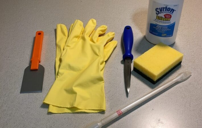 Essential tools for silicone sealant removal, including gloves, a scraper, and rubbing alcohol.