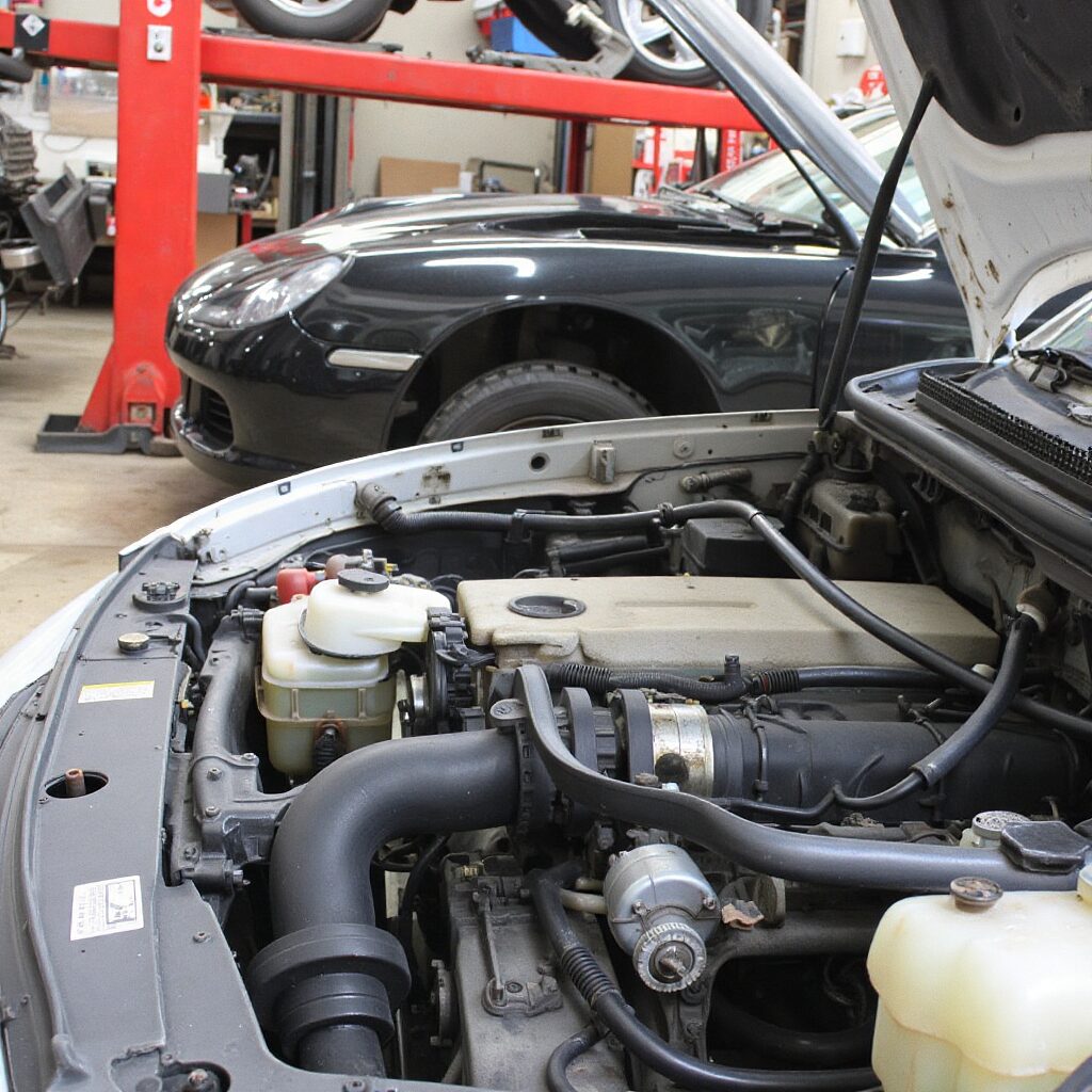 A car with its hood open, ready for minor repairs in a workshop.